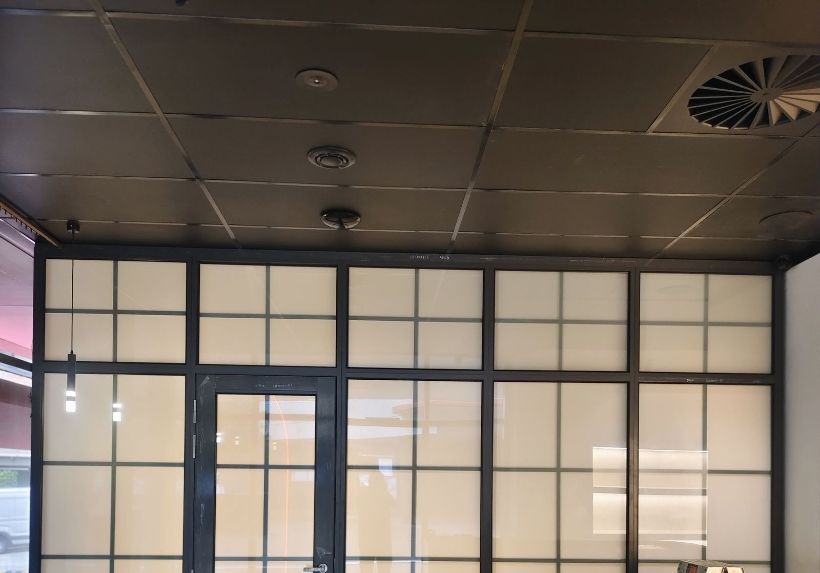 Black grid-glazed aluminium partition and door in an office fit-out, Alexandria NSW